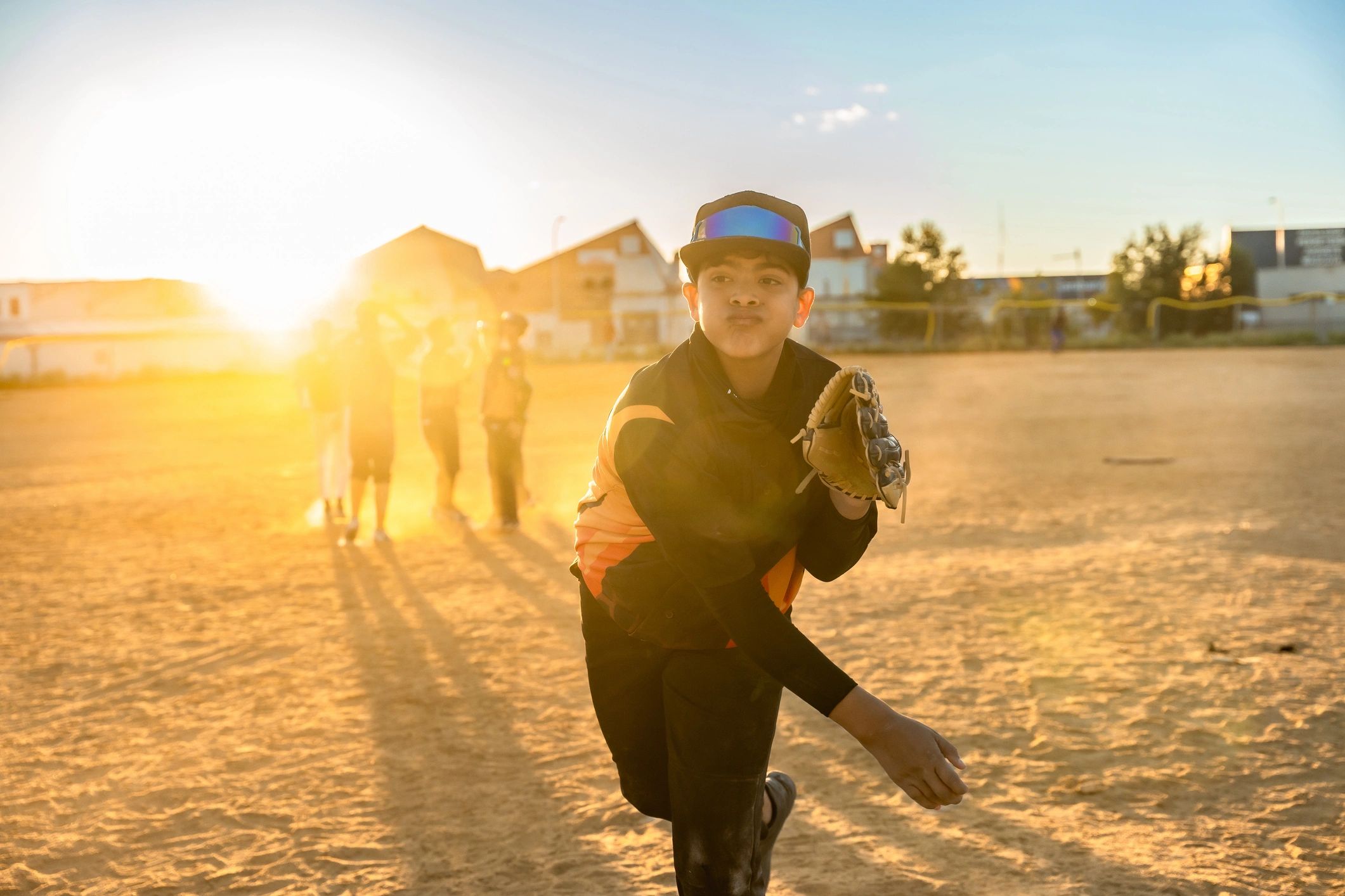 Young baseball pitcher throwing during a sunset game